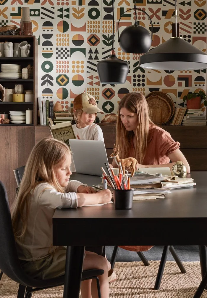 Mama z dwójką dzieci w kolorowej jadalni z różnorodnymi lampami i wzorzystą tapetą